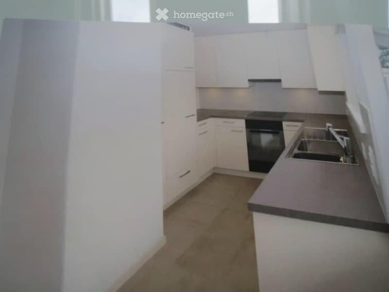 Modern kitchen with white cabinets, dark countertops, and stainless steel appliances including a sink and oven.
