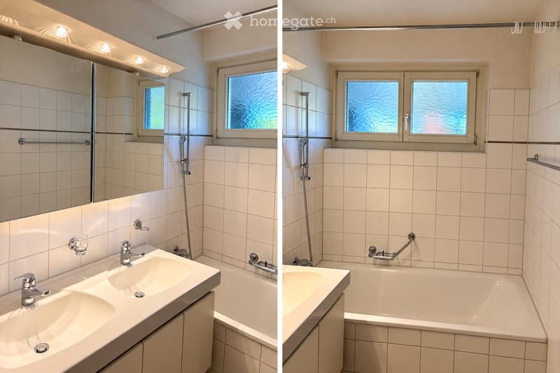 Modern bathroom with white tiled walls, a double sink, a bathtub, a large mirror, and a shower area with a handheld showerhead and handrail.
