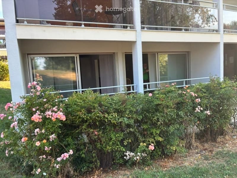 Balcony with outdoor furniture, surrounded by flowering bushes and greenery.