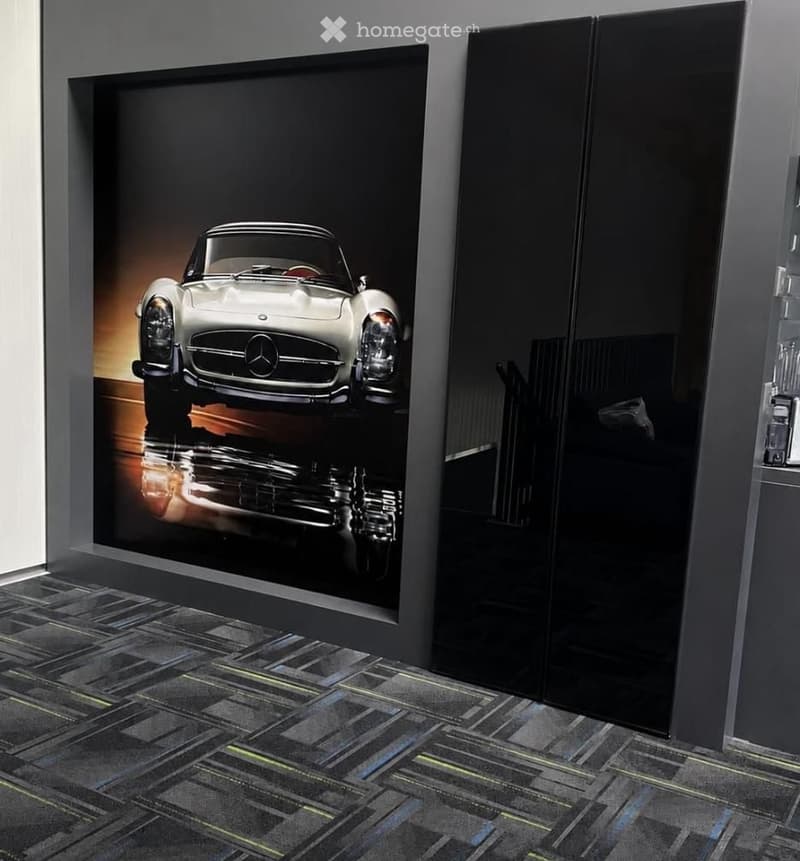 Modern interior with a large framed picture of a classic car on the wall and a sleek black wardrobe.