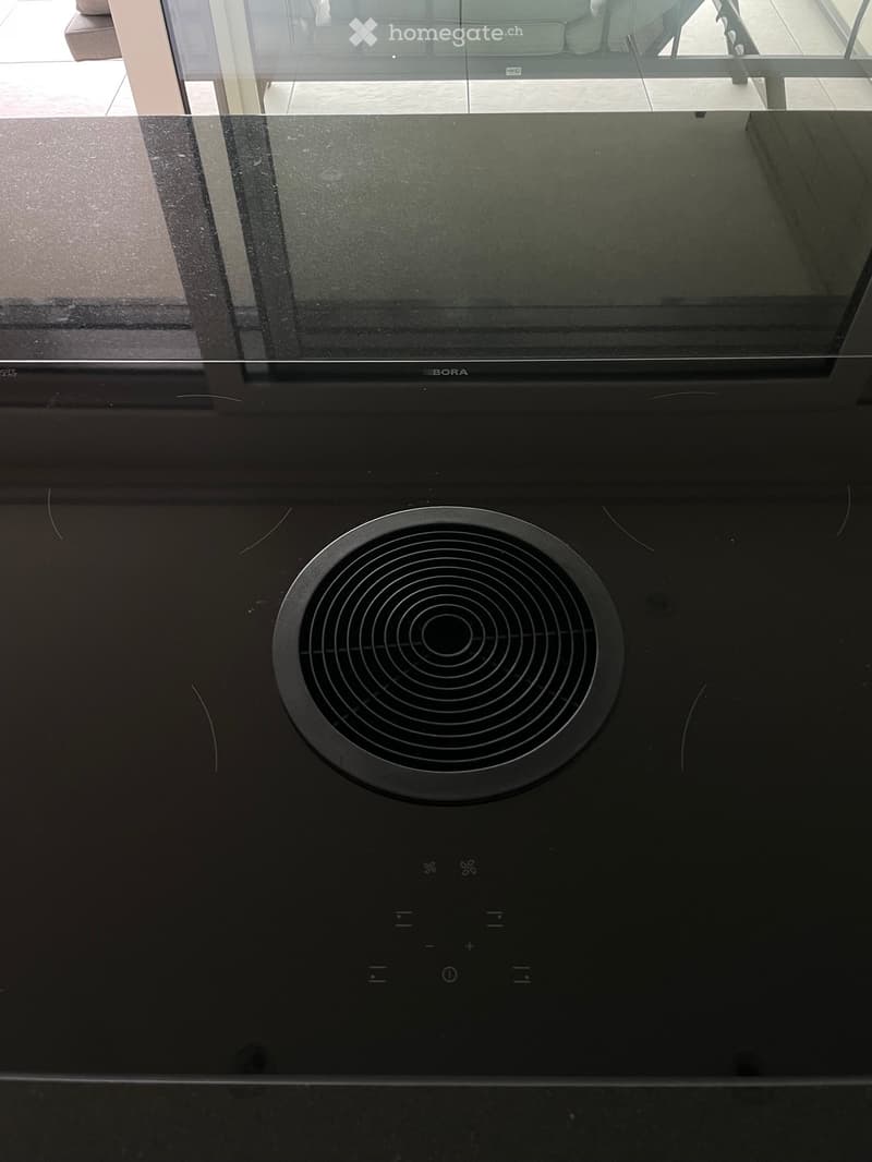 Modern black induction cooktop with circular cooking zones and control panel.