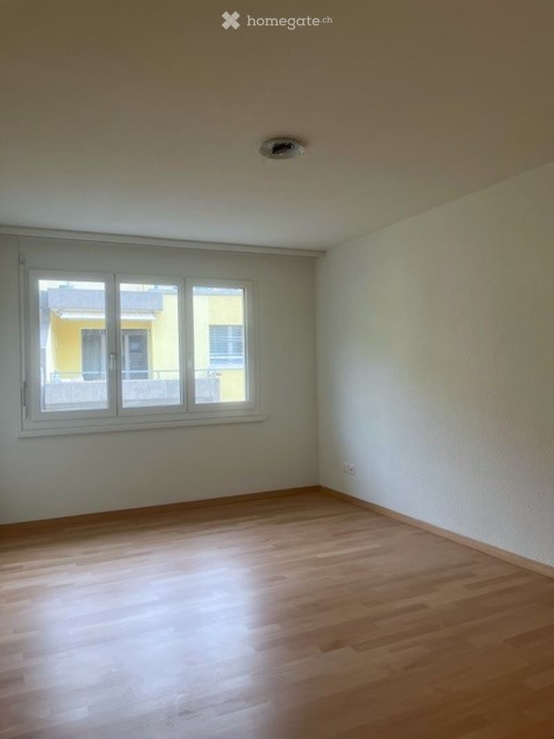 Empty room with wooden flooring, white walls, and a large window with white frame. No furniture or equipment present.
