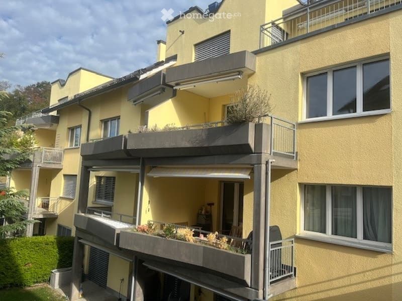 Multi-story residential building with yellow facade, multiple balconies, and windows.
