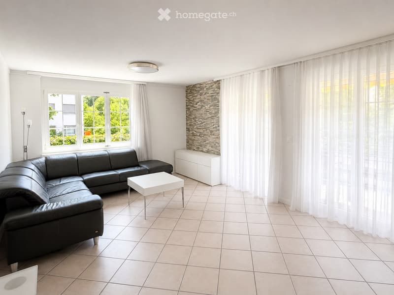 Modern living room with a black leather sectional sofa, white coffee table, white cabinet, and large windows with white curtains.