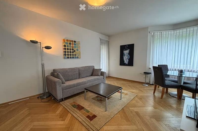 Modern living and dining area with a grey sofa, coffee table, dining table with chairs, floor lamp, and artwork on the walls.