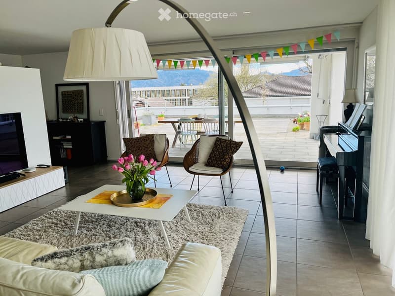 large white floor lamp, white sofa, coffee table with flower vase, carpet, flat screen tv, glass doors leading to balcony