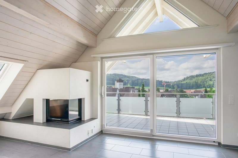 Modern living room with a built-in fireplace, large windows, and a view of the countryside.
