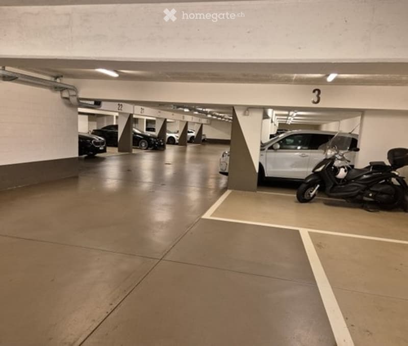 Underground parking area with several parked cars, including a scooter, and numbered parking spots.