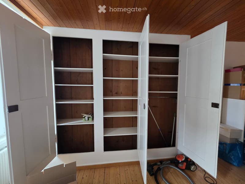 Empty room with wooden floor and white built-in shelving unit. No furniture or equipment visible.