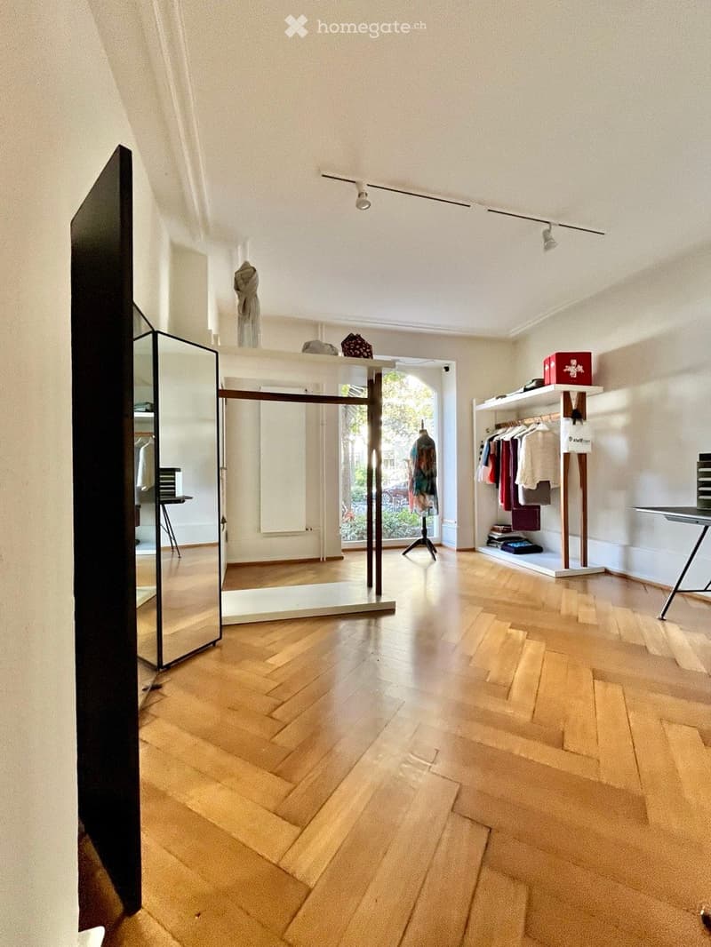 Empty room with wooden flooring, white walls, and large windows allowing natural light. No furniture or equipment present.