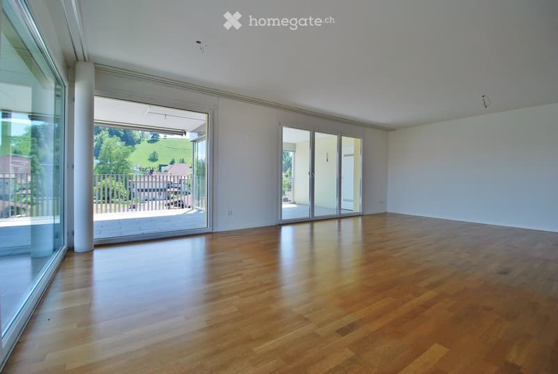 Empty room with wooden flooring, large glass sliding doors leading to a balcony, and white walls.