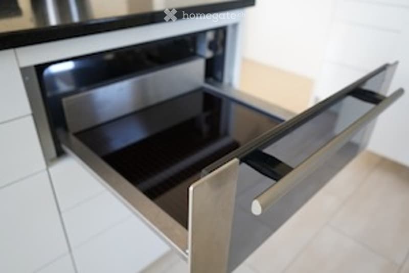 Close-up view of modern kitchen cabinetry with open drawers and shelves, featuring sleek metallic finishes and clean lines.