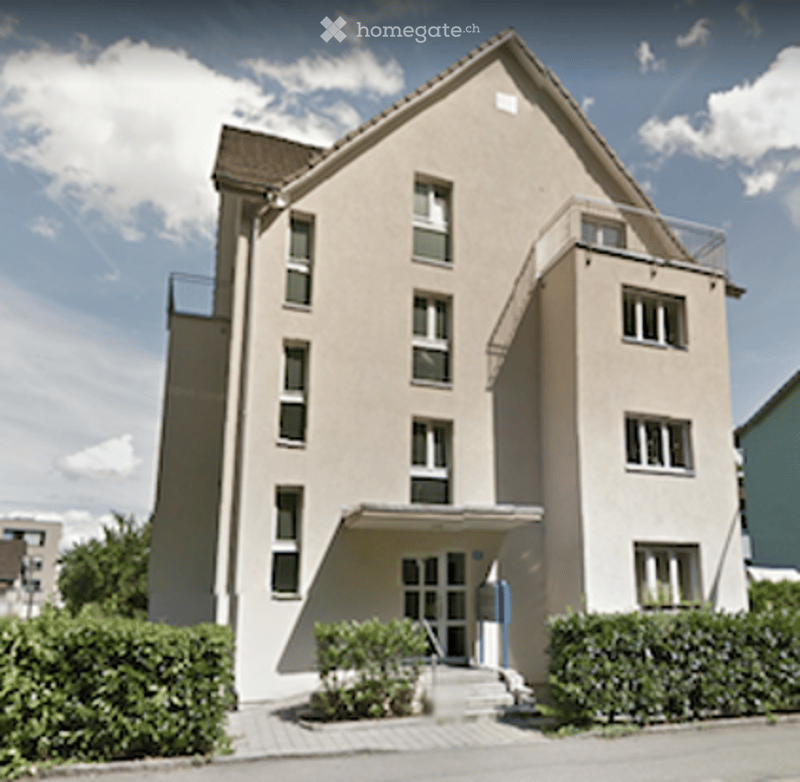 Modern multi-story residential building with beige facade, multiple windows, and balconies.