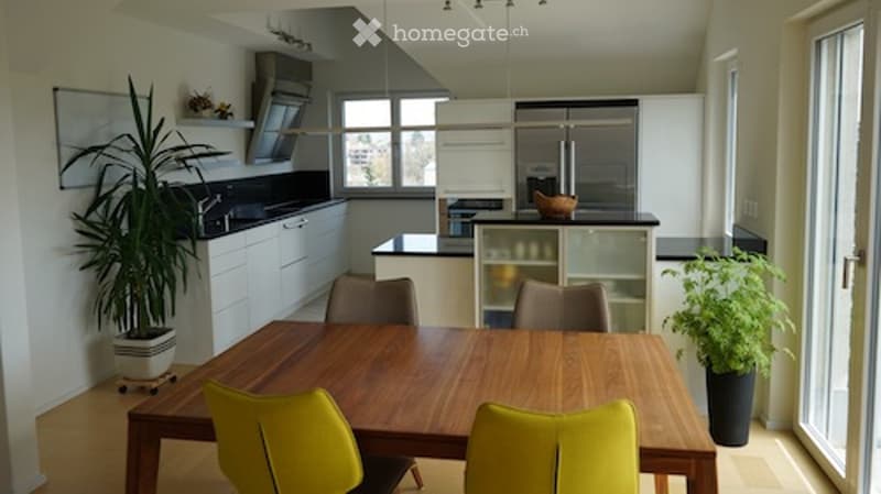 Modern kitchen and dining area with white cabinets, wooden dining table, yellow chairs, and potted plants.