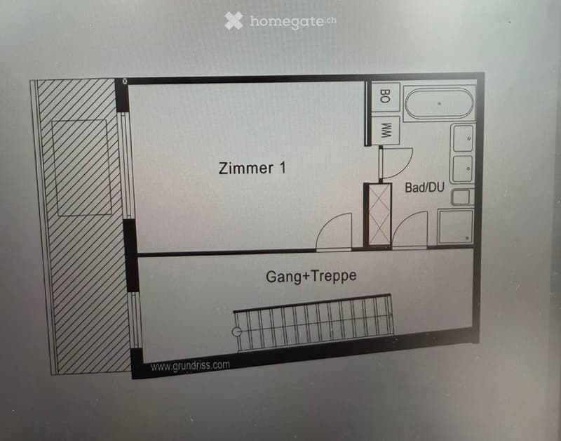 Floor plan showing a room labeled "Zimmer 1", a bathroom/toilet area, a hallway/stairs area, and a small storage or closet space.