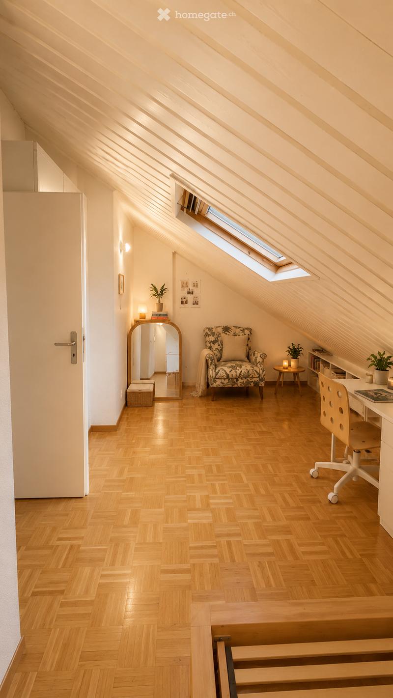 Cozy attic room with wooden flooring, slanted ceilings, and skylights. Features a patterned armchair, small table, desk with chair, mirror, and decorative plants.