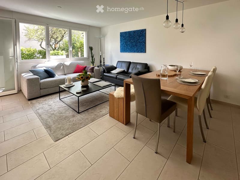 Modern living and dining area with grey sofa, black leather sofa, coffee table, dining table, chairs, and decorative items.