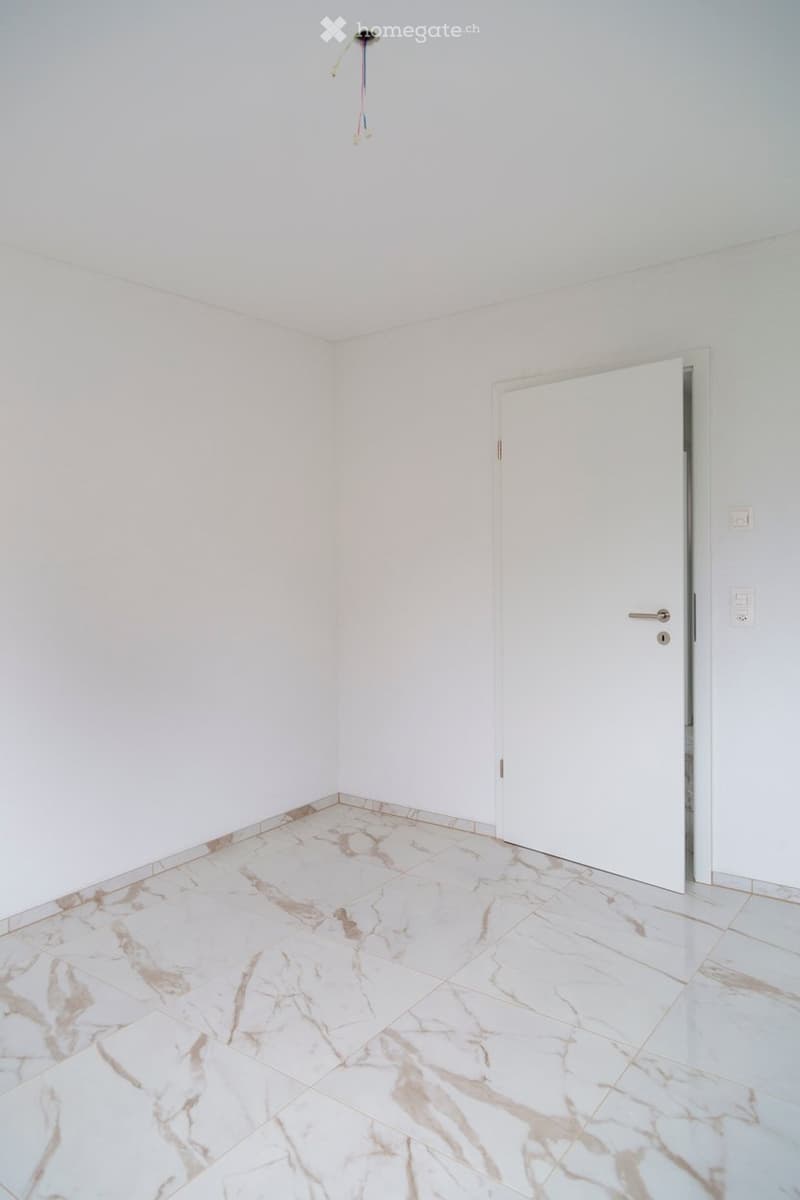 Empty room with white walls, marble tiled floor, and a white door.