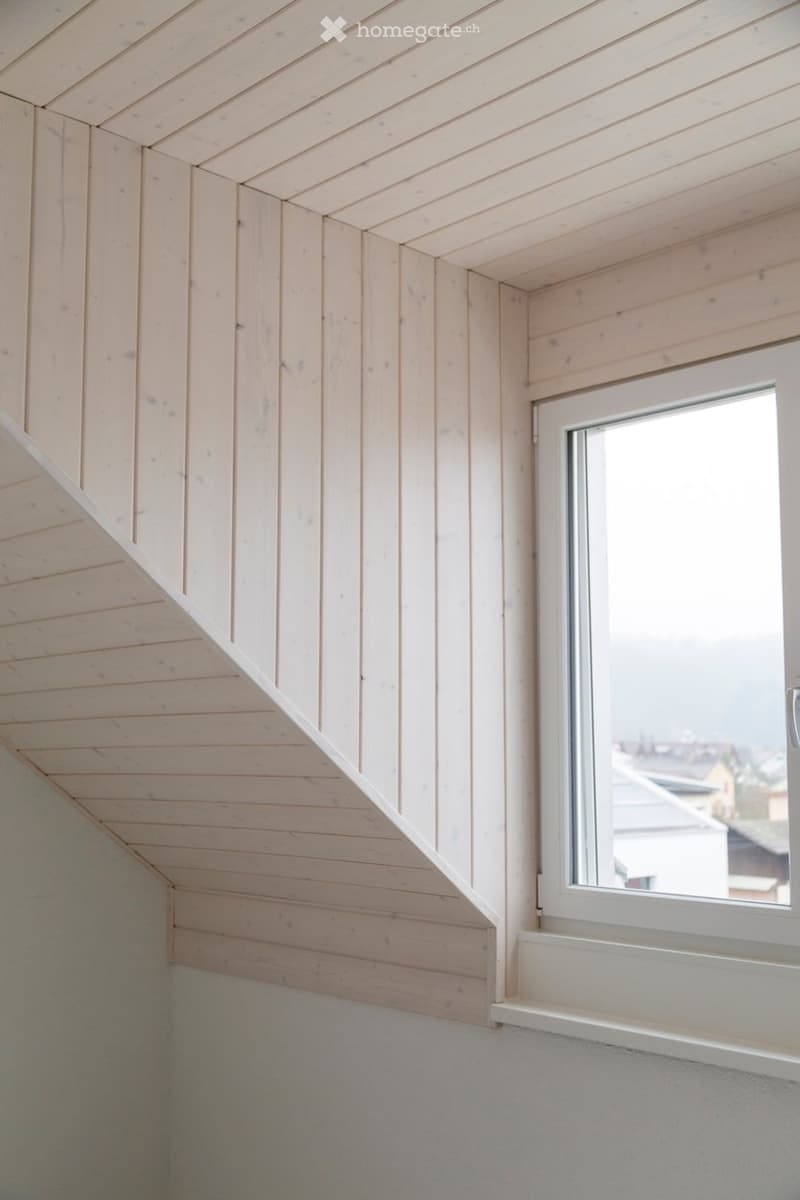 Empty room with wooden paneled walls and ceiling, a single window with white frame, and a white window sill.