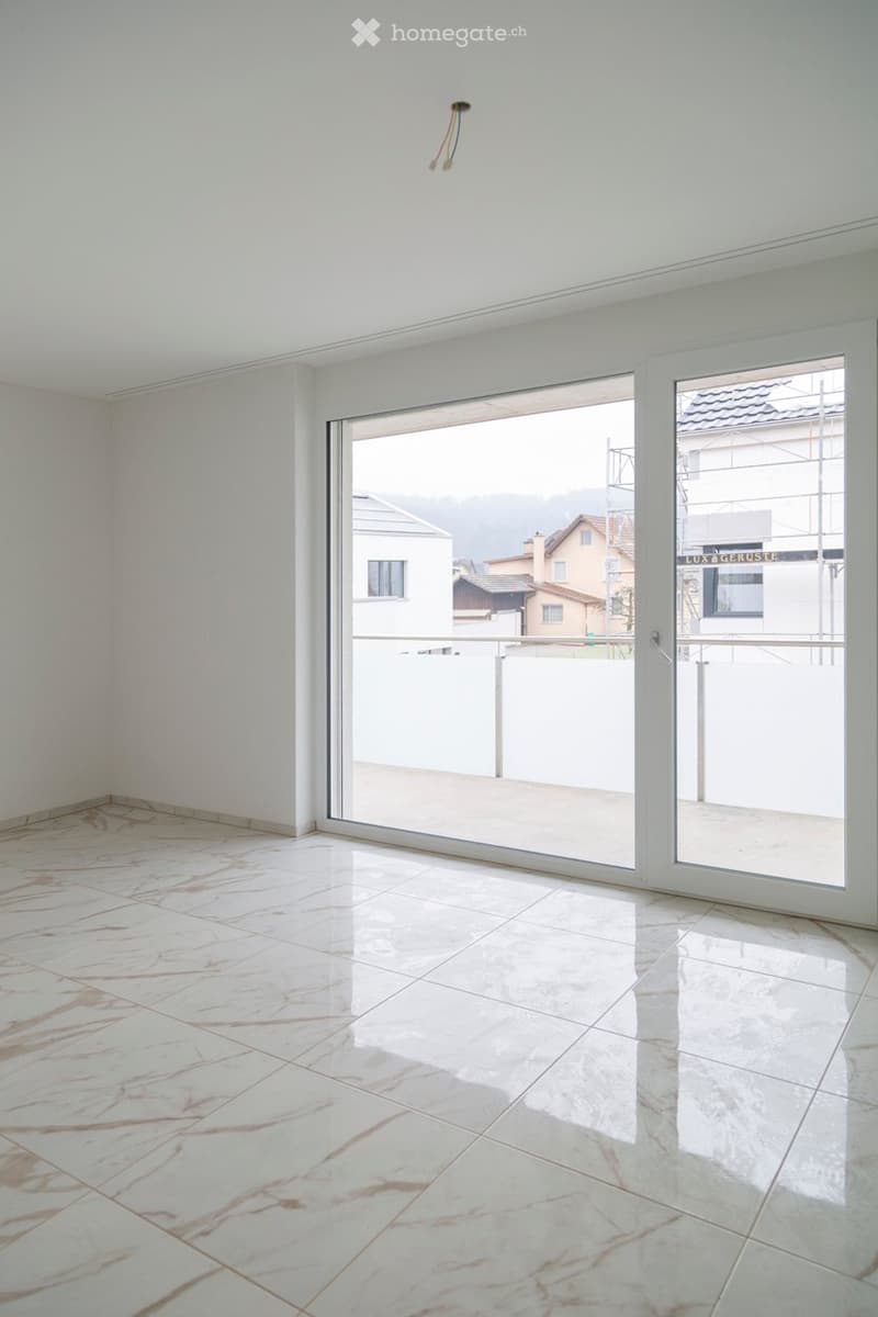 Empty room with white walls, marble flooring, and large sliding glass doors leading to a balcony.