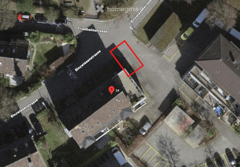 Aerial view of a residential building with a pitched roof, surrounded by neighboring houses and parked cars.