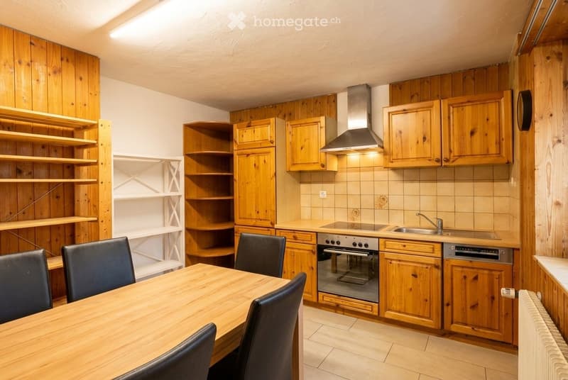 Cozy kitchen with wooden cabinets, a dining table with chairs, an oven, and a sink.