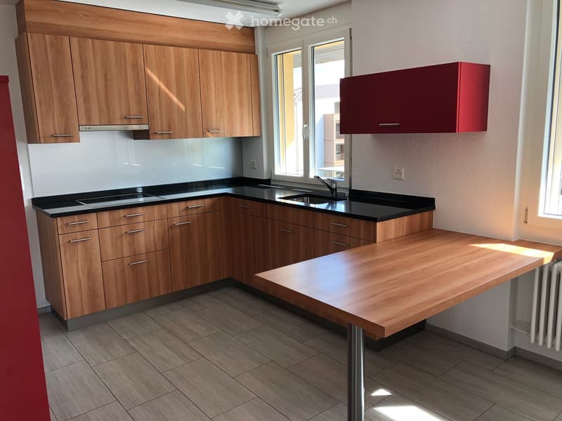 Modern kitchen with wooden cabinets, black countertops, a sink, and a central island.