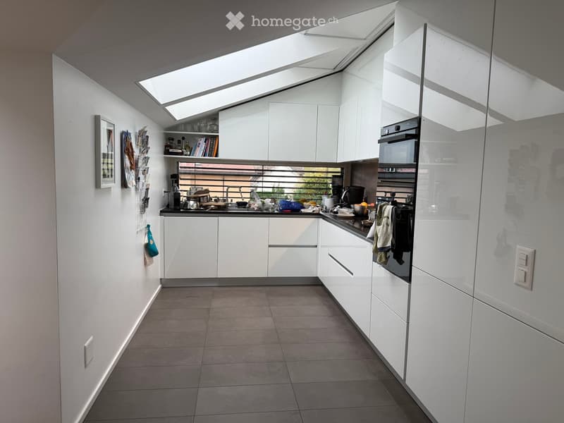 Modern kitchen with white cabinets, stainless steel appliances, and a large skylight above the island.