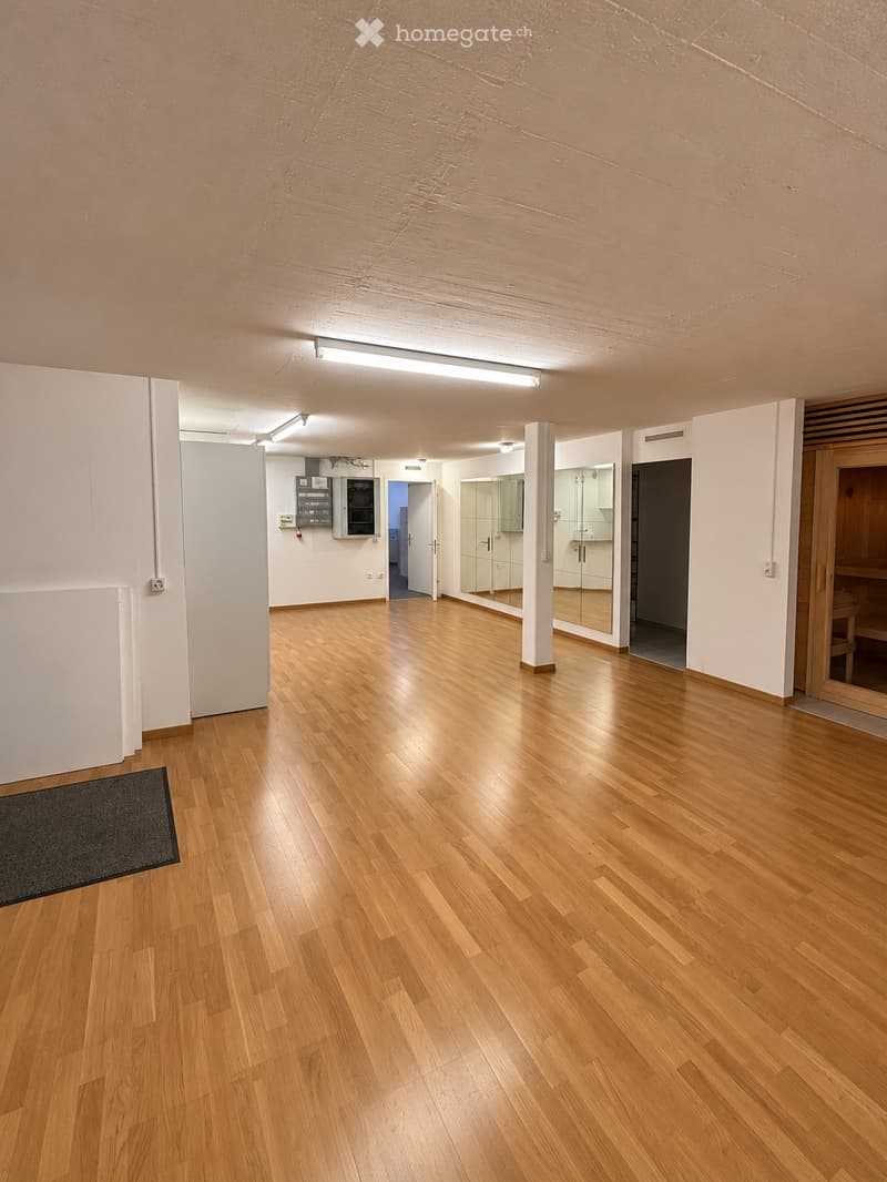 Empty room with wooden flooring, white walls, and a few doors leading to other spaces. No furniture or equipment is present.