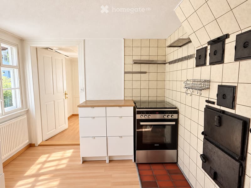 Modern kitchen with white cabinets, stainless steel oven, wooden countertop, and tiled backsplash.
