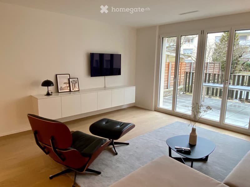 white walls, black sofa, white tv cabinet, mounted tv, large windows, red chair, black ottoman, black table, vase, grey carpet