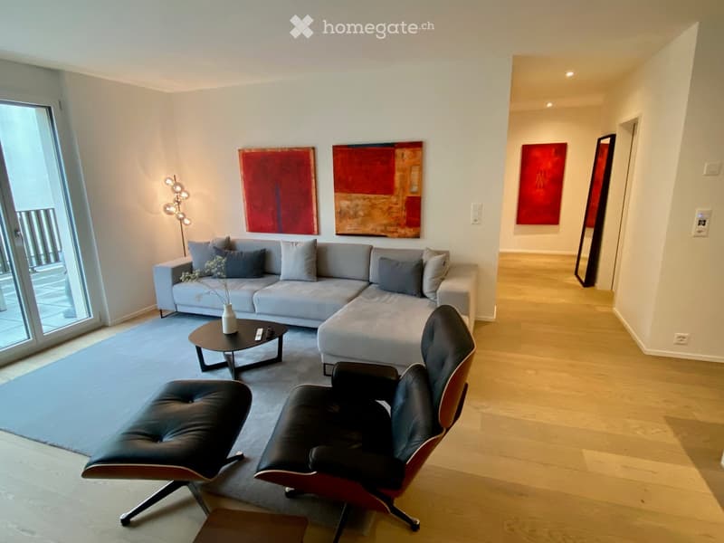 L-shaped couch, coffee table, decorative pillows, lamps, paintings, carpet, sliding glass door leading to a balcony with a balcony view