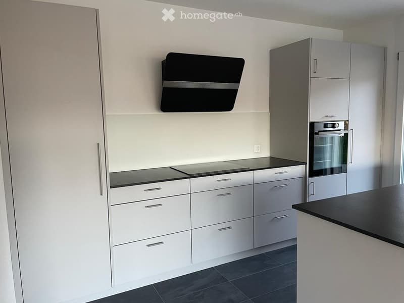 Modern kitchen with white cabinets, stainless steel appliances, and a black countertop.