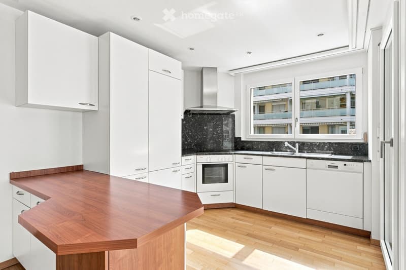 Modern kitchen with white cabinets, wooden countertop, stainless steel appliances, and a black marble backsplash.