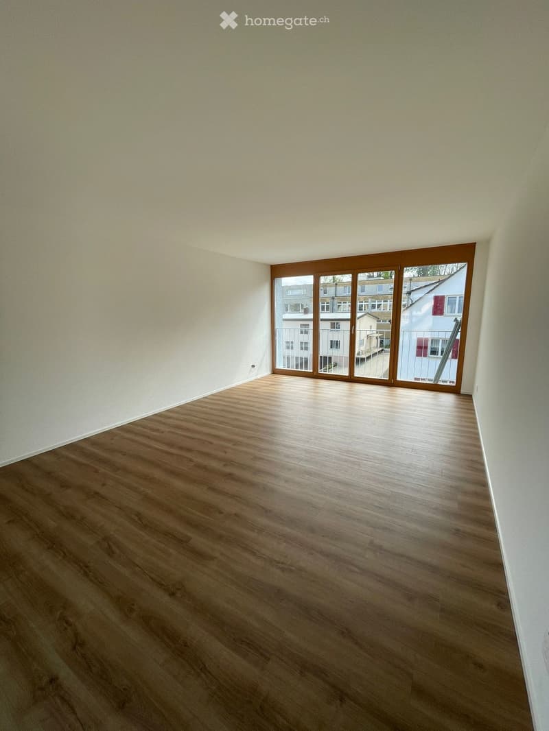 Empty room with wooden flooring and large sliding glass doors leading to a balcony.