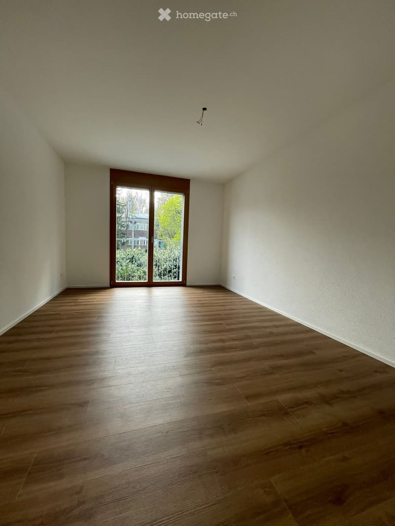 Empty room with wooden flooring and large sliding glass door leading to a balcony or outdoor area.