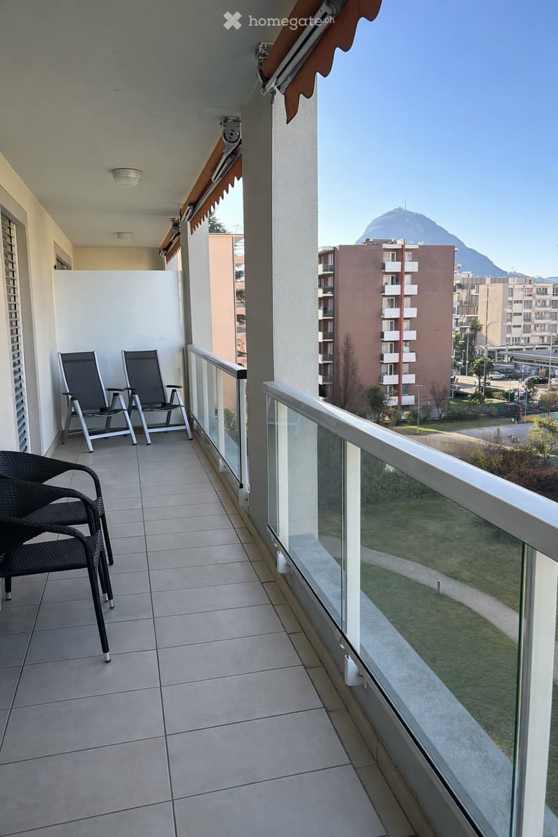 spacious balcony with metal chairs, tiled floor, glass railings, beautiful landscape view