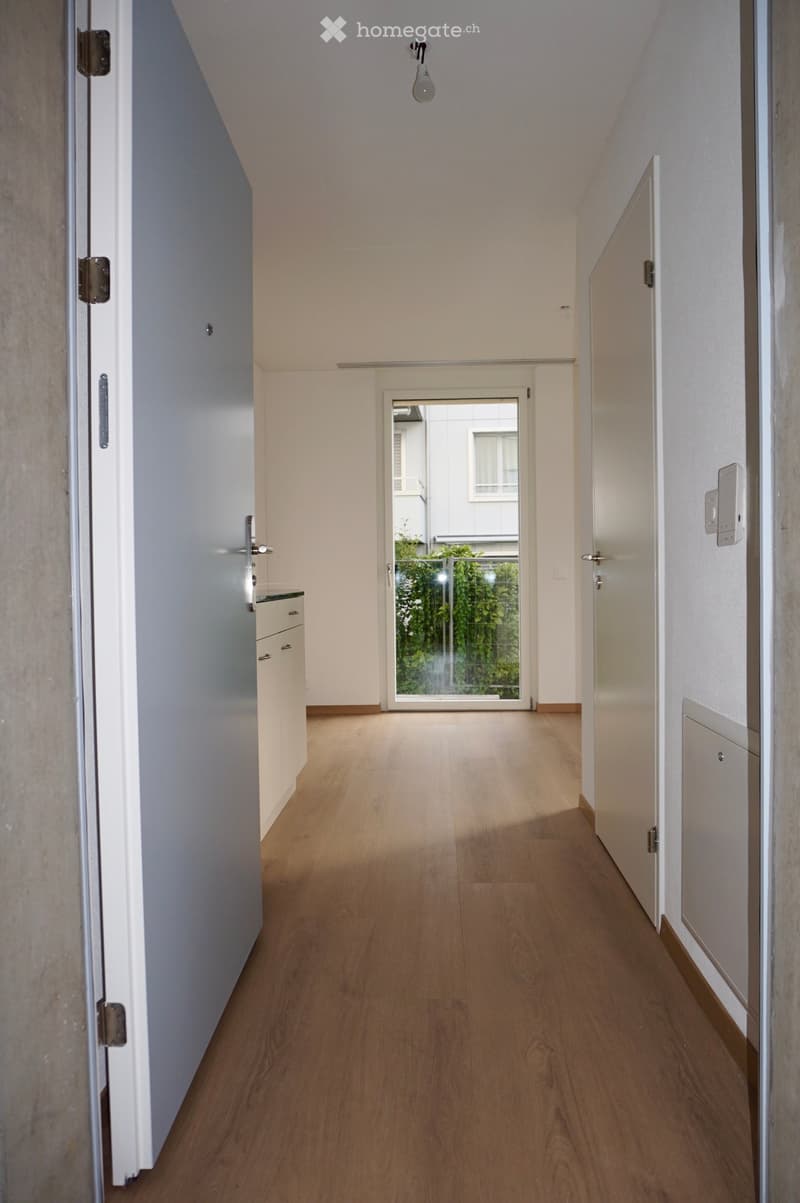 Empty hallway with wooden flooring, white walls, and several doors leading to different rooms.
