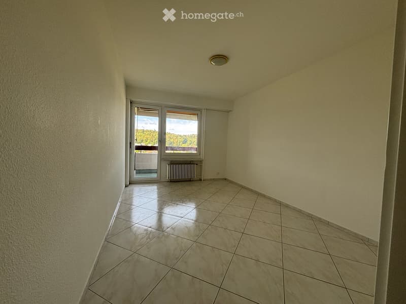 Empty room with tiled floor, light-colored walls, and a sliding glass door leading to a balcony.