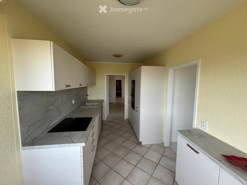 Modern kitchen with white cabinets, marble countertops, and a tiled floor. Features a sink, faucet, and an oven.