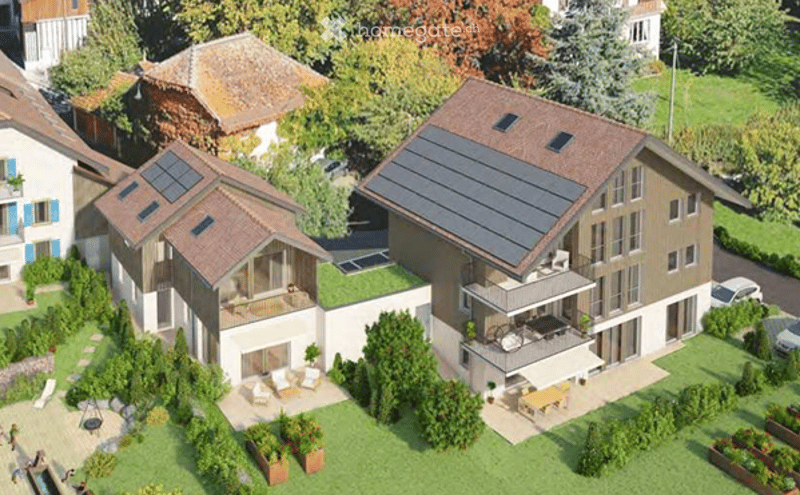 Aerial view of a modern residential complex with multiple houses, solar panels on roofs, balconies, a swimming pool, and a parking area.