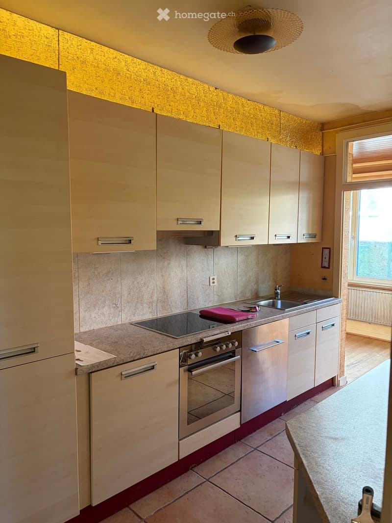 Modern kitchen with light wood cabinets, stainless steel appliances, and a granite countertop. Features an oven, sink, and faucet.