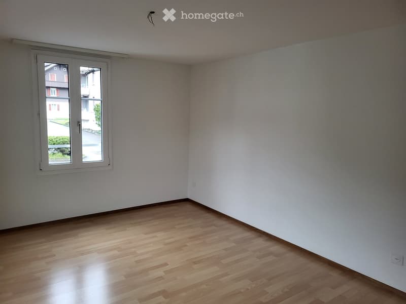Empty room with wooden flooring and white walls, featuring a single window with a view of the outside.