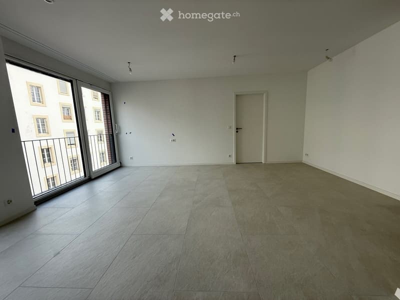 Empty room with tiled floor, white walls, large sliding glass door leading to a balcony, and a closed door to another room.