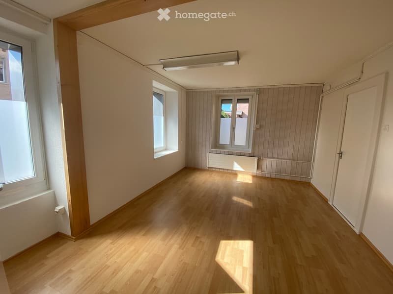 Empty room with wooden flooring, white walls, and multiple windows allowing natural light. No furniture or equipment present.