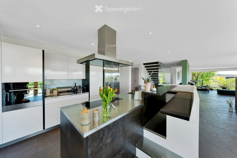 Modern kitchen with white cabinets, stainless steel appliances, island with seating, and decorative items on the counter.
