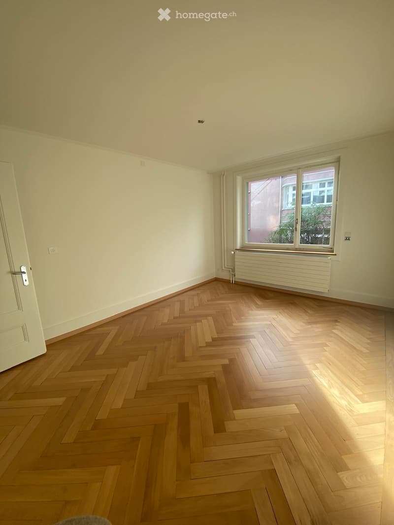 empty room, parquet floor, white walls, white door, windows with radiators