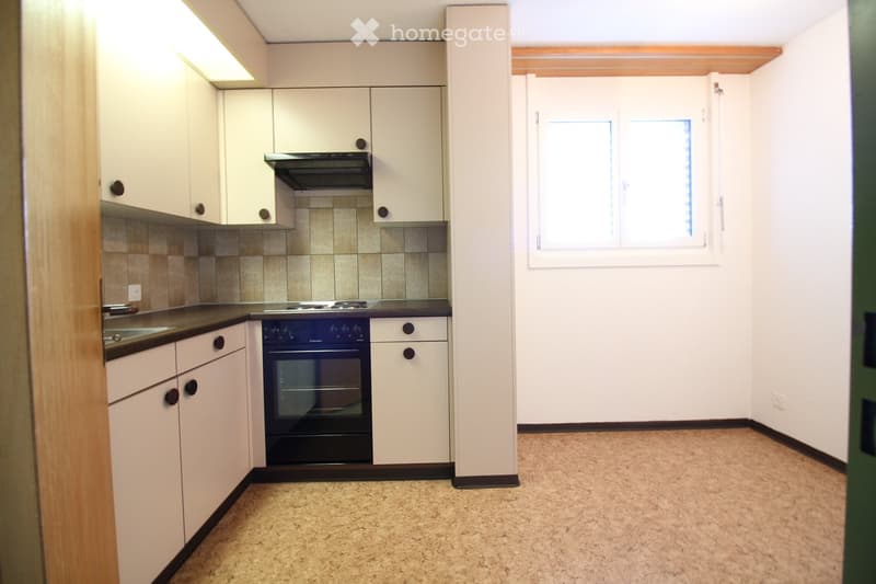 Modern kitchen with white cabinets, a black oven, a stove, and a sink, featuring tiled backsplash and carpeted floor.