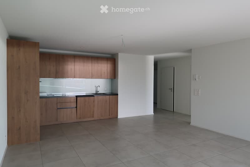 Modern kitchen with wooden cabinets, tiled floor, and a sink with a faucet. The space is clean and unfurnished, with white walls and a neutral color palette.