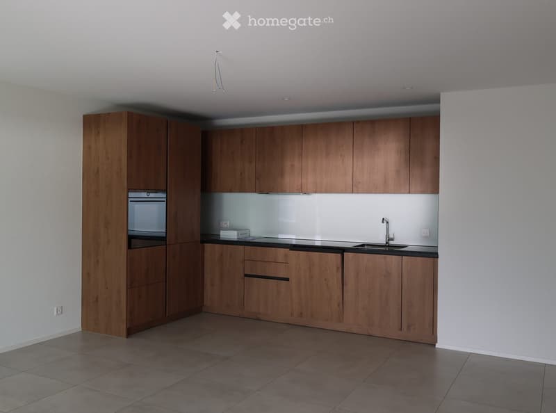 Modern kitchen with wooden cabinets, a sink, a faucet, and an oven. The space features a tiled floor and white walls.